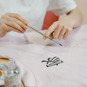 A person meticulously painting an intricate design on fabric using a brush.