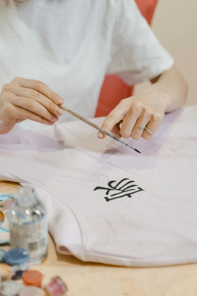 A person meticulously painting an intricate design on fabric using a brush.