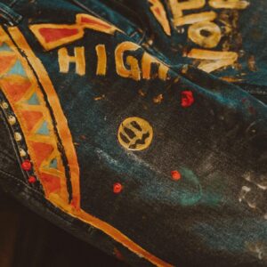 Close-up of artistically painted denim jeans with bold yellow designs and patterns.