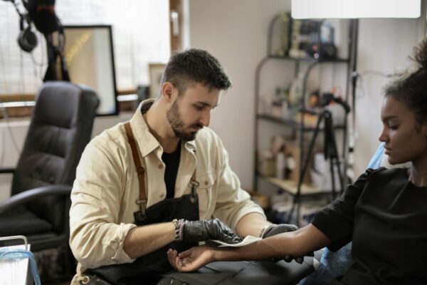 Tattoo artist meticulously creating a design on a client's arm in a studio setting.