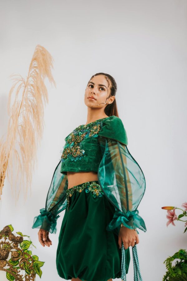 Woman in a stylish green traditional outfit posing indoors with elegant decor.
